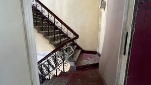 A staircase with ornate metal railings and a red-tiled floor.