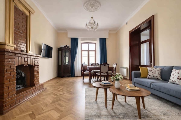 Elegant living room with chandelier, herringbone floor and decorative inactive fireplace.