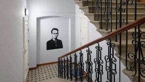 Eine Treppe mit aufwendiger schwarzer Metallgeländerung, einem gemusterten Boden und einer weißen Tür mit einem gerahmten Porträt.