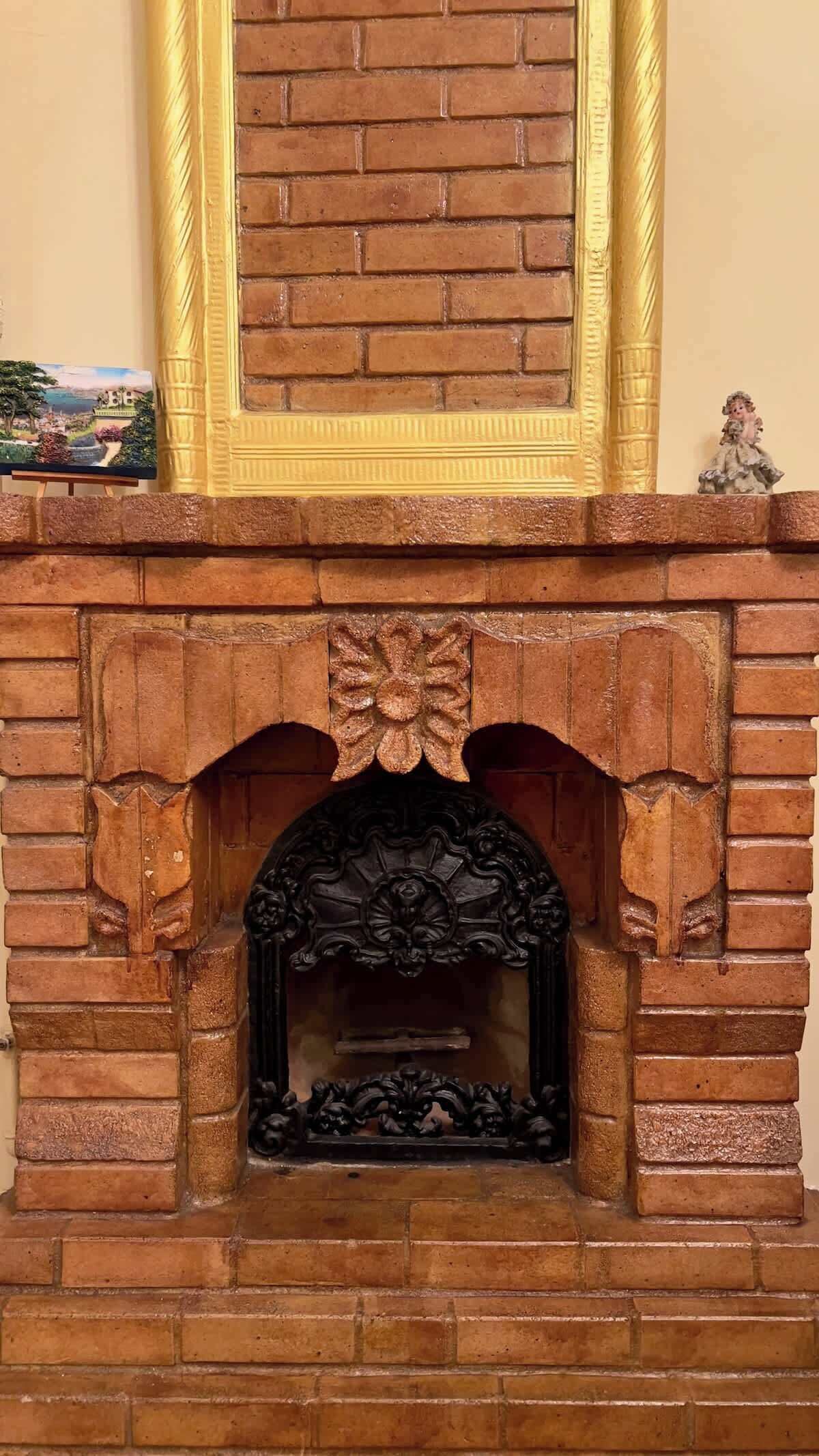 A brick fireplace with a decorative arch and a gold-framed mirror above it.