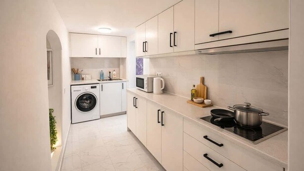 A modern kitchen with white cabinetry, a built-in washing machine, a microwave, and a stove.
