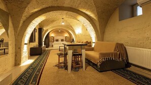 A cozy room with a high arched ceiling, a sofa, a table, and a patterned rug.