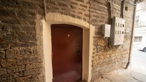 A brown door with a small window, a tiled floor, and a brick wall.