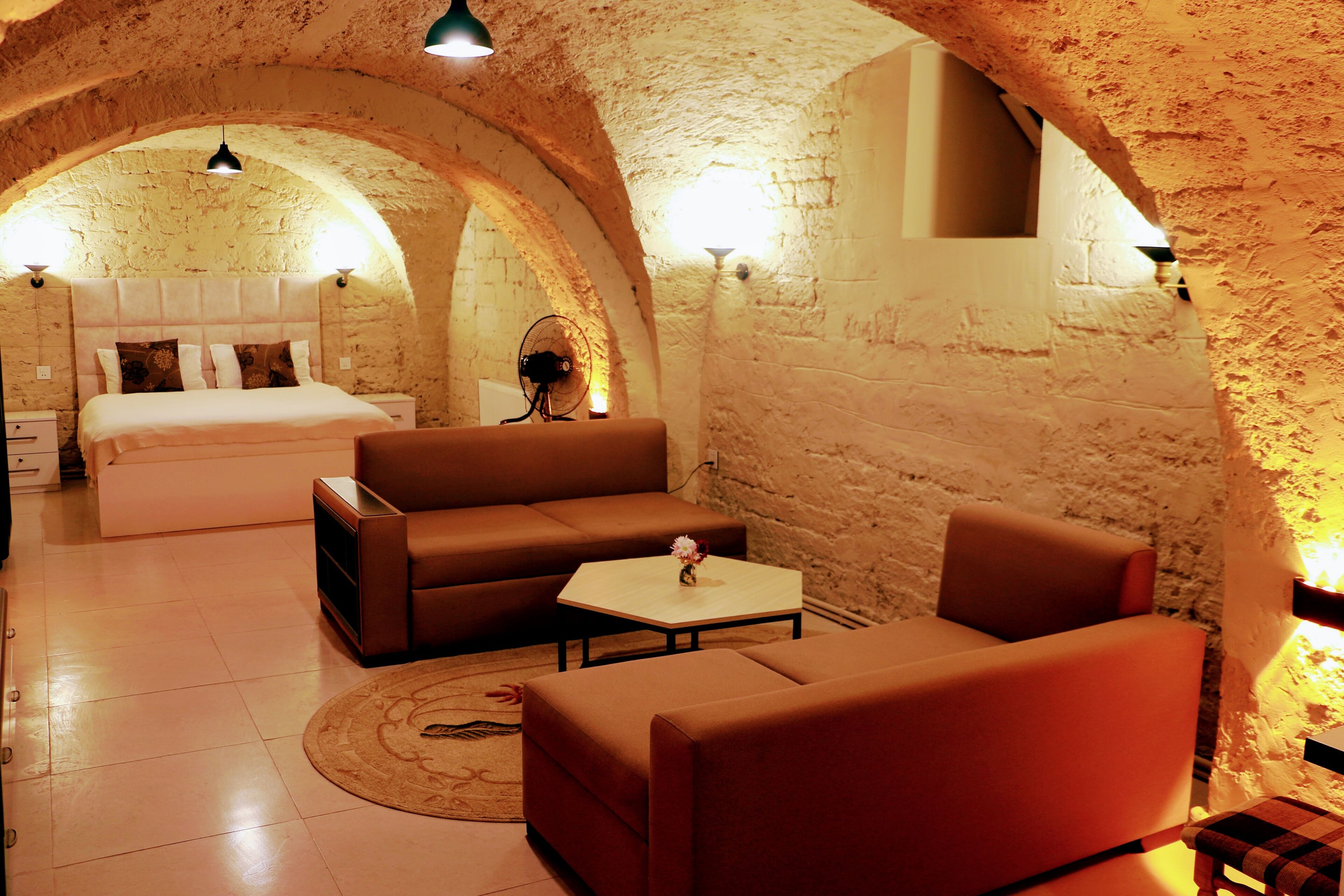 Una habitación acogedora con una cama, un sofá, una mesa de centro y un ventilador.