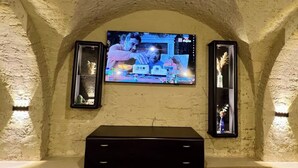 A television mounted on a textured wall with two side tables.