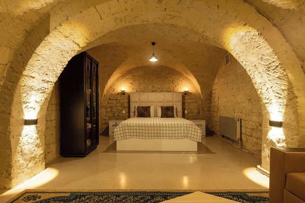 Stone-vaulted bedroom with a queen-size bed and warm lighting.