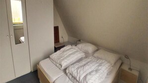 Une chambre à coucher avec un lit, une armoire et une petite table de chevet.