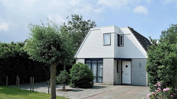 Une maison moderne à deux étages, dotée d’un toit en pente, d’une porte d’entrée et d’un petit jardin.