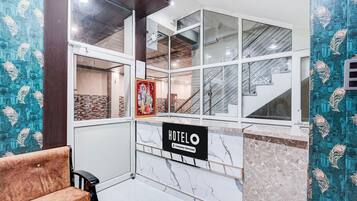 A hotel reception area with a marble counter, a bench, and a staircase.