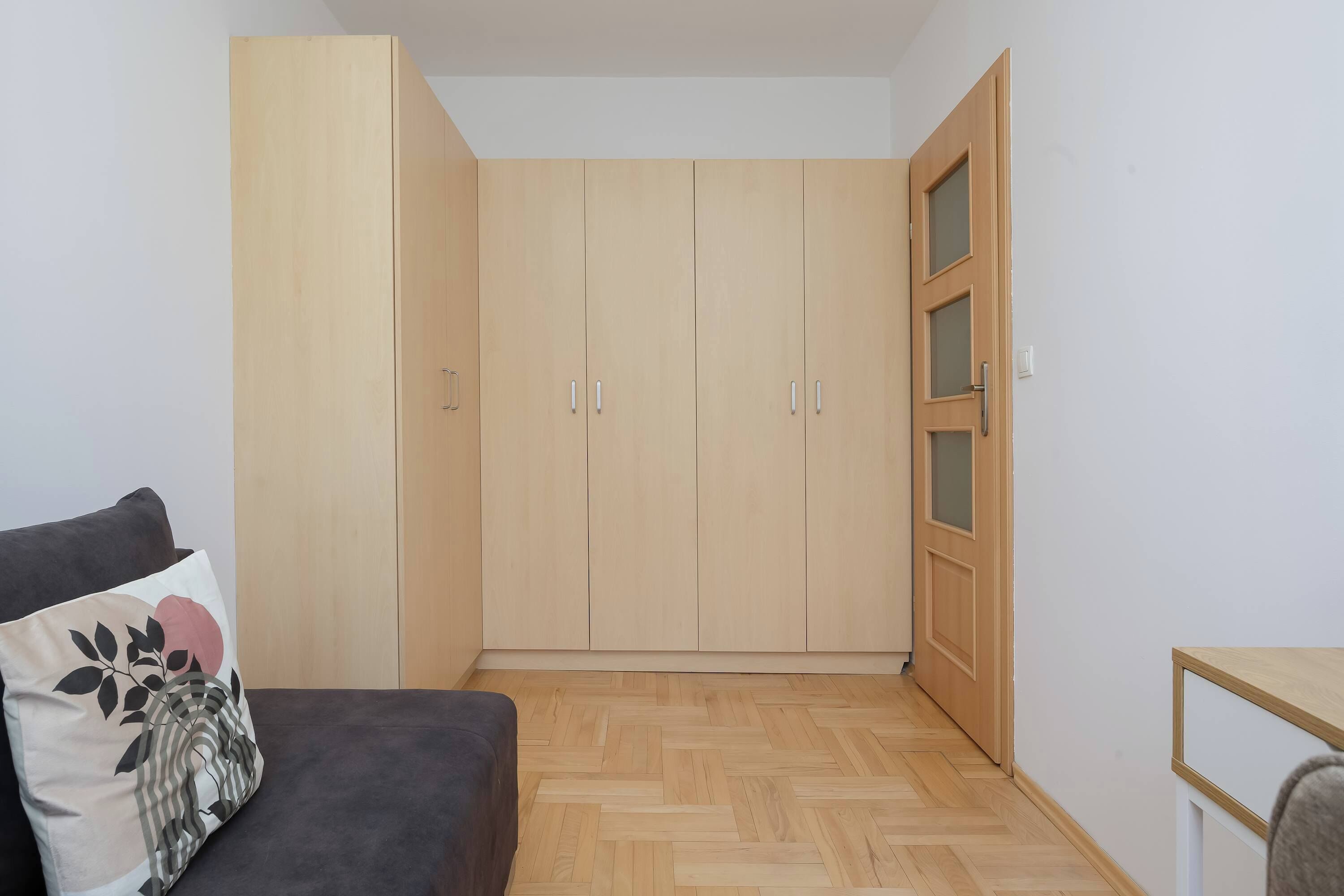 Una habitación con armario, cama y una pequeña mesa.