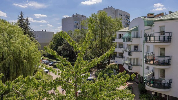 A multi-story residential building with balconies, a parking area, and surrounding greenery. - Bright Apartment with a Balcony | A Place to Work (Warszawa)