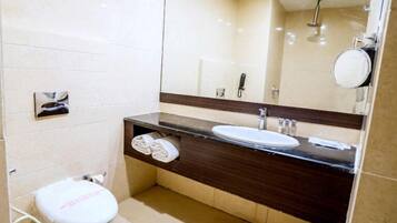 Une salle de bain équipée de toilettes, d’un lavabo, d’un miroir et d’un porte-serviettes.