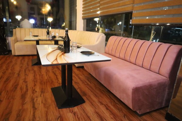 Un interior moderno con piso de madera, una mesa blanca con base negra, un sofá rosa y un sofá beige.