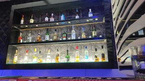 A bar with multiple shelves of liquor bottles. - Holiday Home (Ranchi)