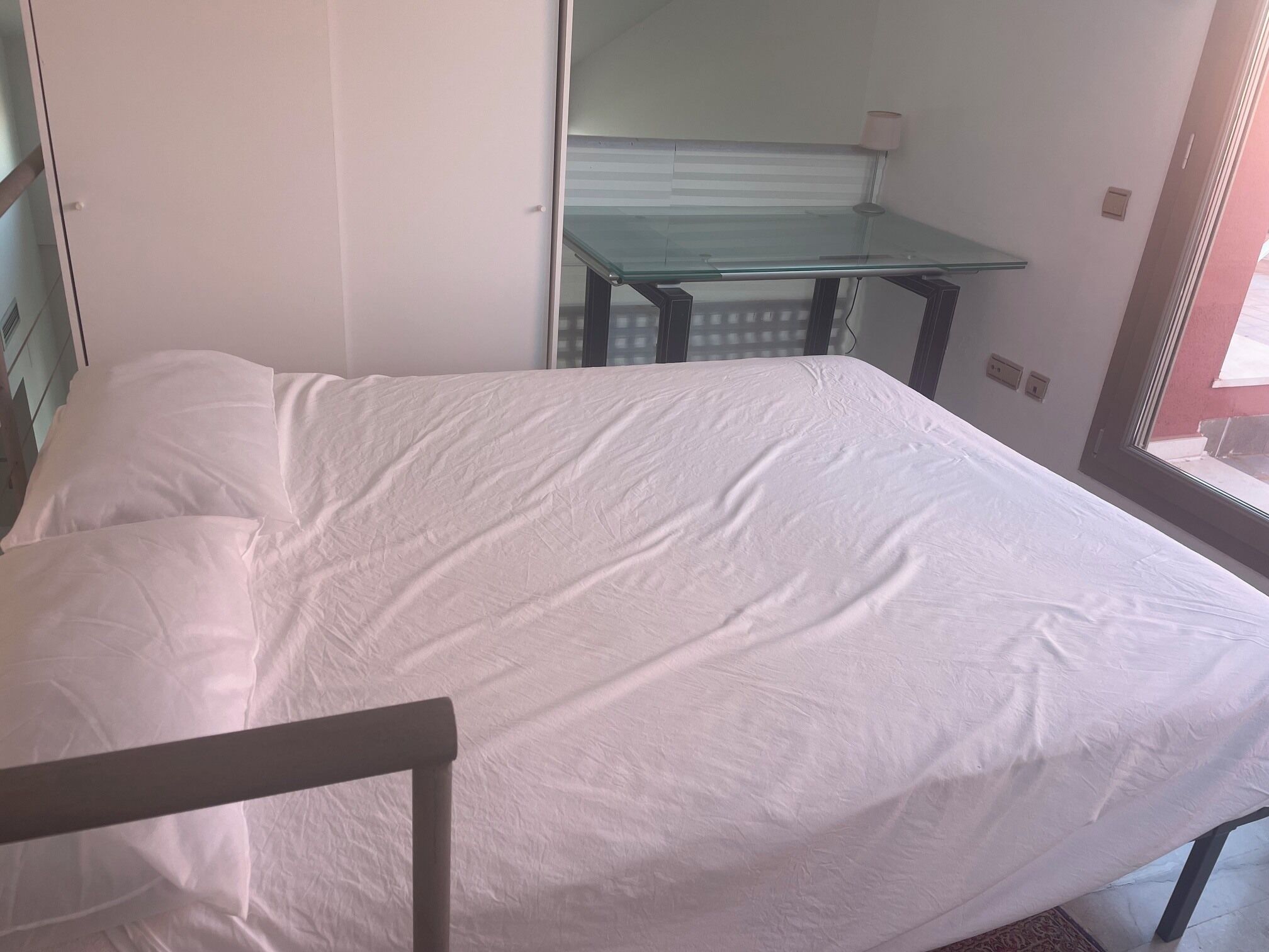Une pièce avec un lit, une petite table et une fenêtre.