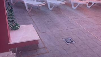 Una terraza con sillones blancos, plantas en macetas y vistas al mar.