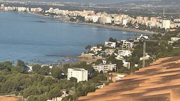 Un paisaje costero con edificios, una playa y montañas al fondo.