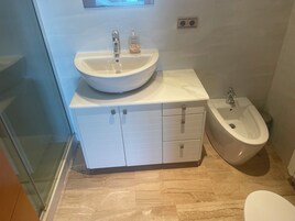 Un baño con lavamanos, bidé y un mueble con cajones.