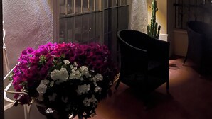Ein Zimmer mit vergittertem Fenster, einem Kaktus und einer Blumenkomposition.