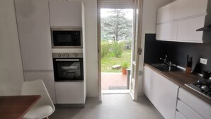 Eine moderne Küche mit weißen Schränken, einem eingebauten Backofen und einem Essbereich mit einem Holztisch und weißen Stühlen.