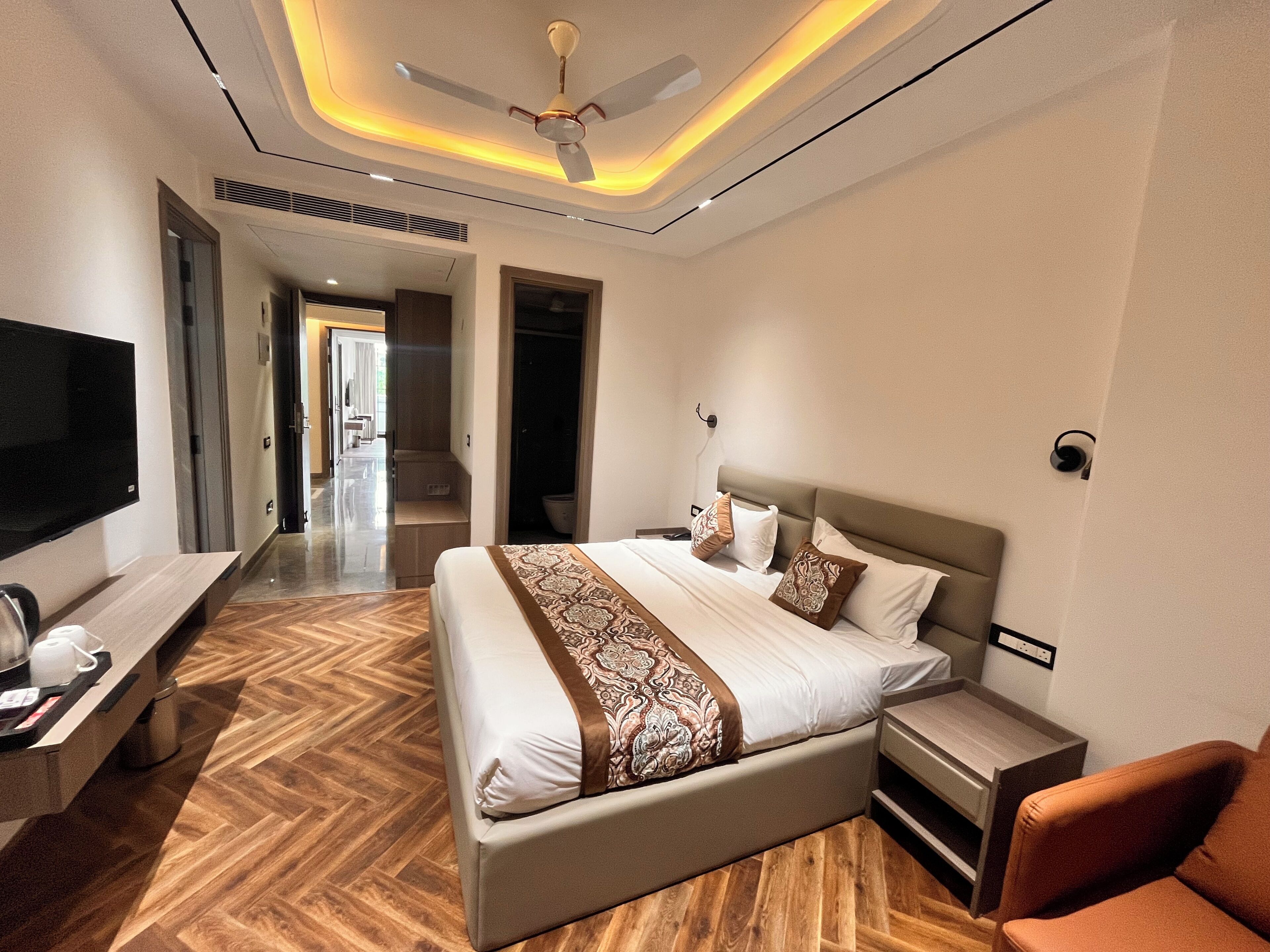 Habitación de hotel moderna con una cama grande, mesitas de noche, un televisor de pantalla plana y un ventilador de techo.