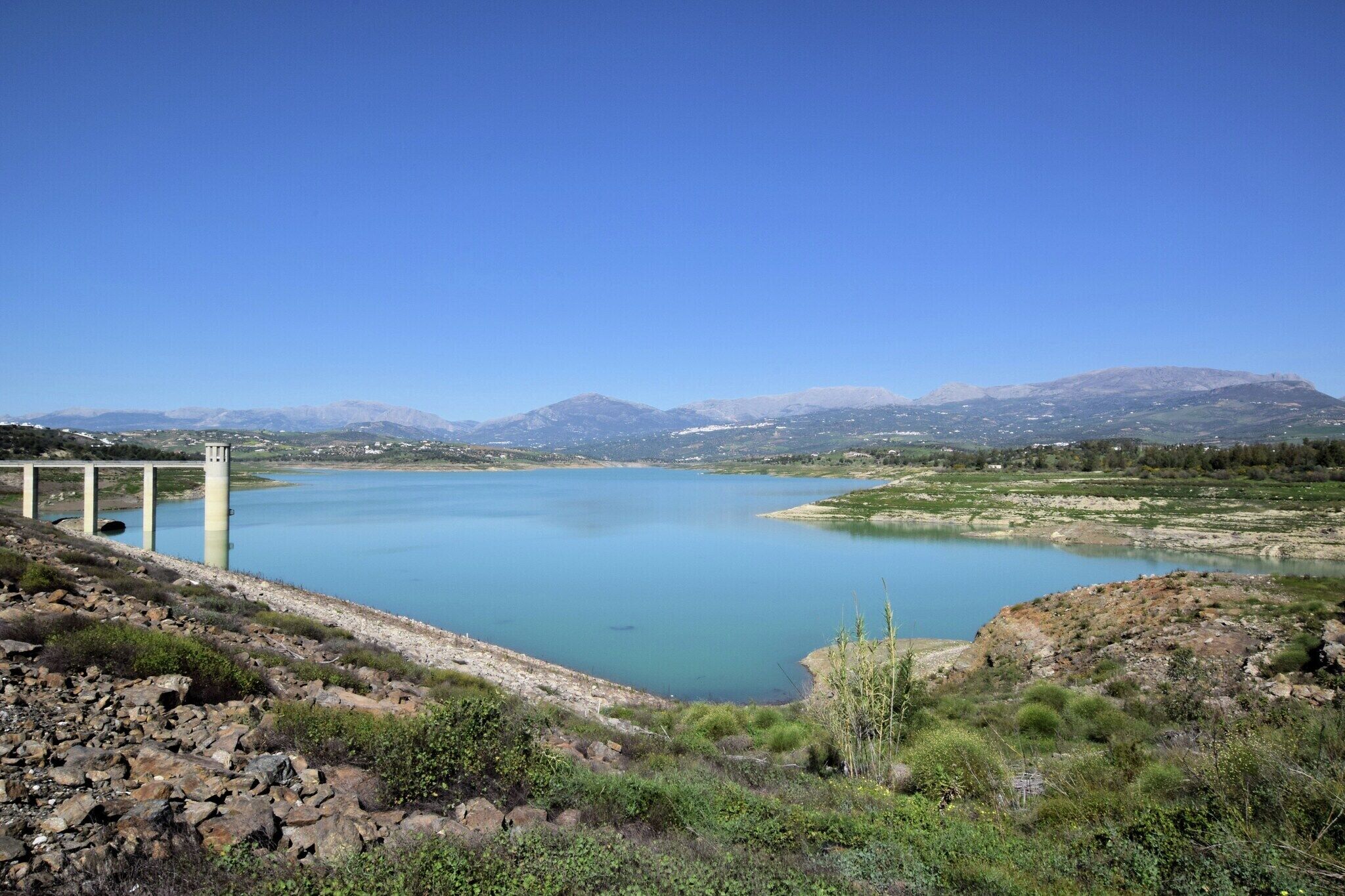 A lake with a dam and mountains in the background.