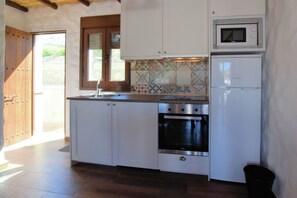 A compact kitchen with white cabinets, a built-in oven, a microwave, and a window above the sink. - Beautiful villa with jacuzzi (Canillas de Albaida)
