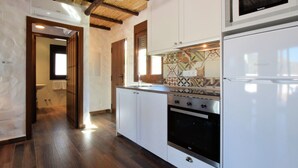 Een keuken met witte kastjes, een kookplaat, een oven, een magnetron en een decoratieve spatwand.