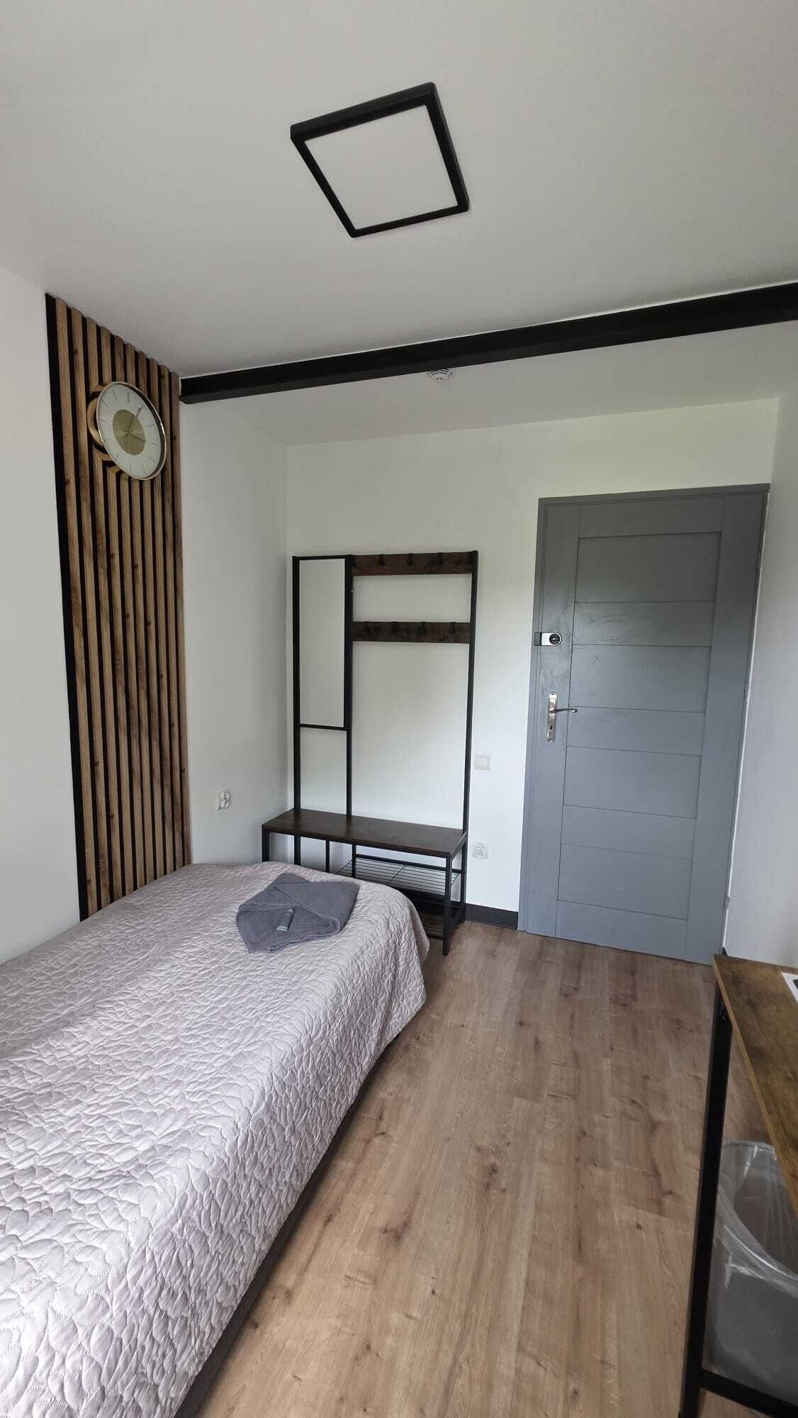A bedroom with a bed, a wooden slat wall, a metal bed frame, a door, and a small table.