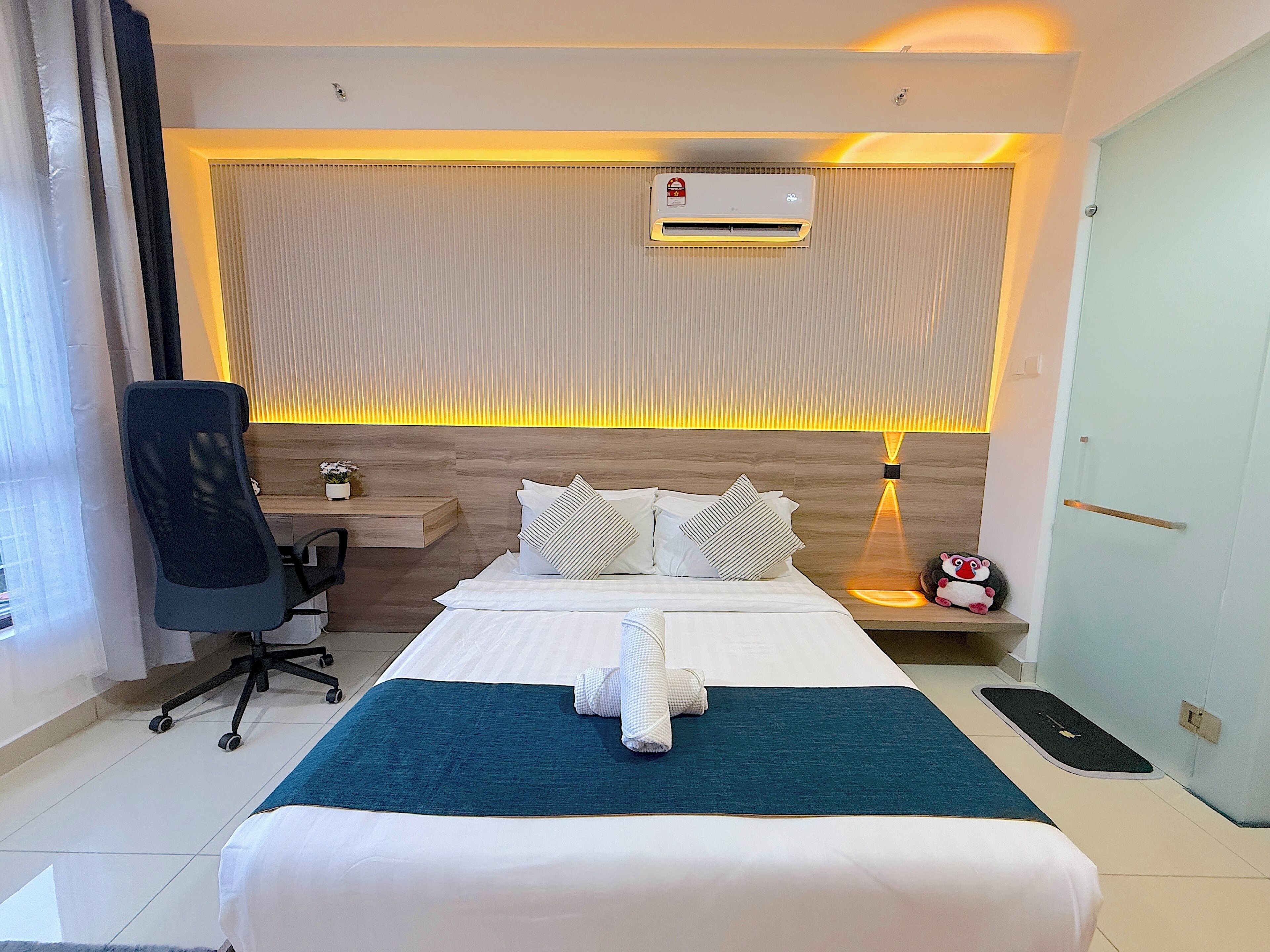 Una habitación de hotel con cama, mesita de noche, silla y aire acondicionado.