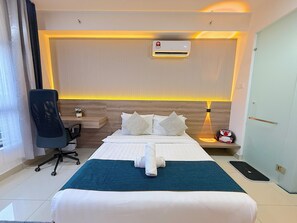Een hotelkamer met een bed, nachtkastje, stoel en een airconditioning.