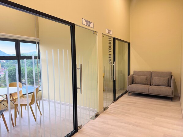 Una sala de reuniones con separador de vidrio, un sofá y una mesa con sillas.
