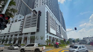 A modern high-rise building with a prominent entrance, traffic lights, and a clear sky. - Astrum Ampang By Serenity Homes (Kuala Lumpur)