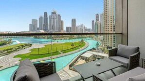 Un balcón con vista al horizonte urbano, una extensa masa de agua y un área ajardinada.
