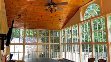 Une pièce avec une table de ping-pong, un plafond en bois et de grandes fenêtres.