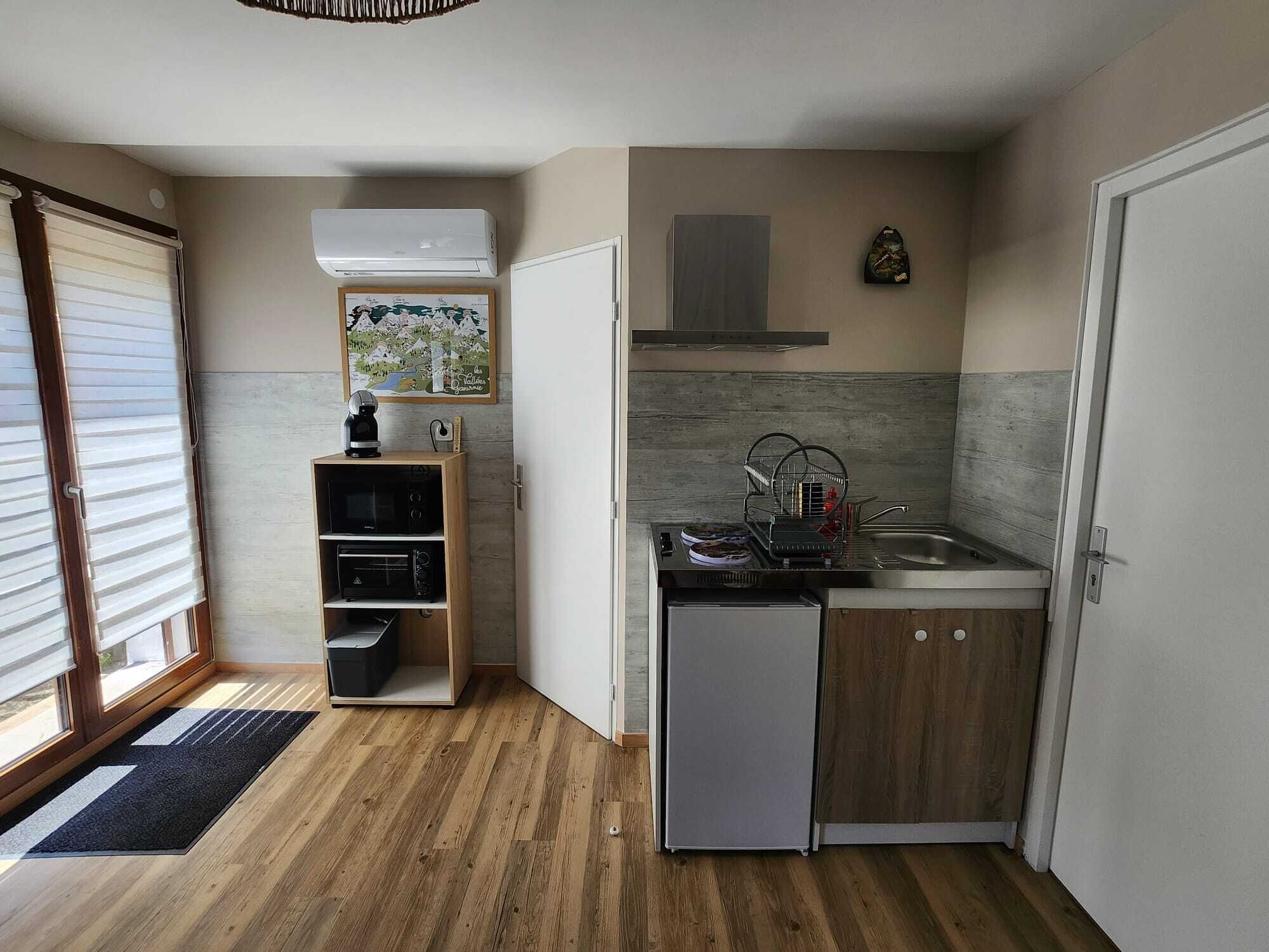 A compact kitchen with a dishwasher, a coffee machine, and a dish rack.