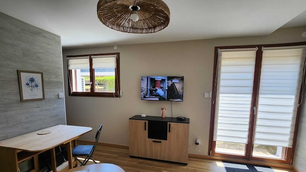Uma cozinha moderna com área de refeições, uma TV na parede e uma janela grande com persianas.