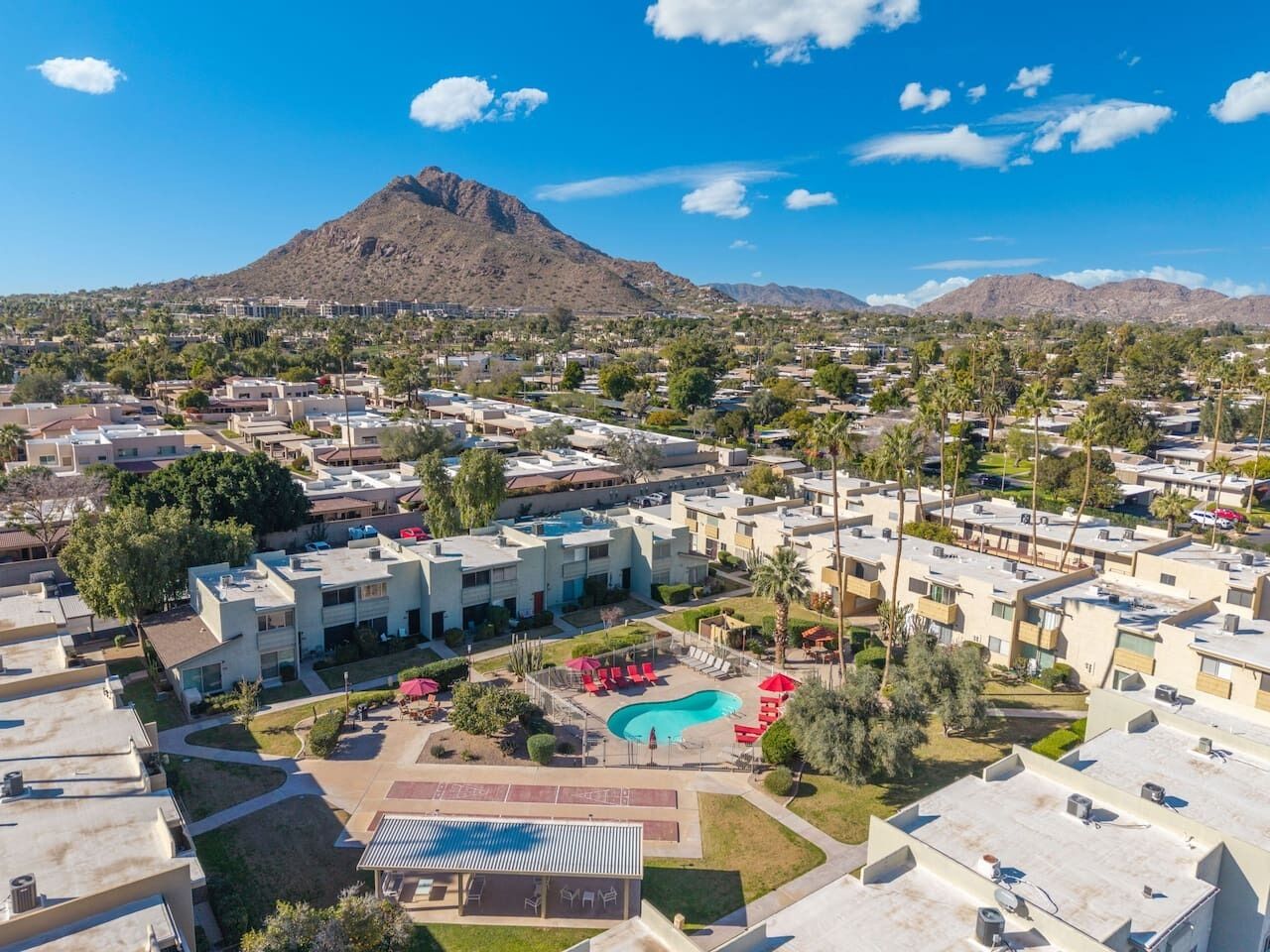 A resort with a central pool, multiple buildings, and a mountain in the background.