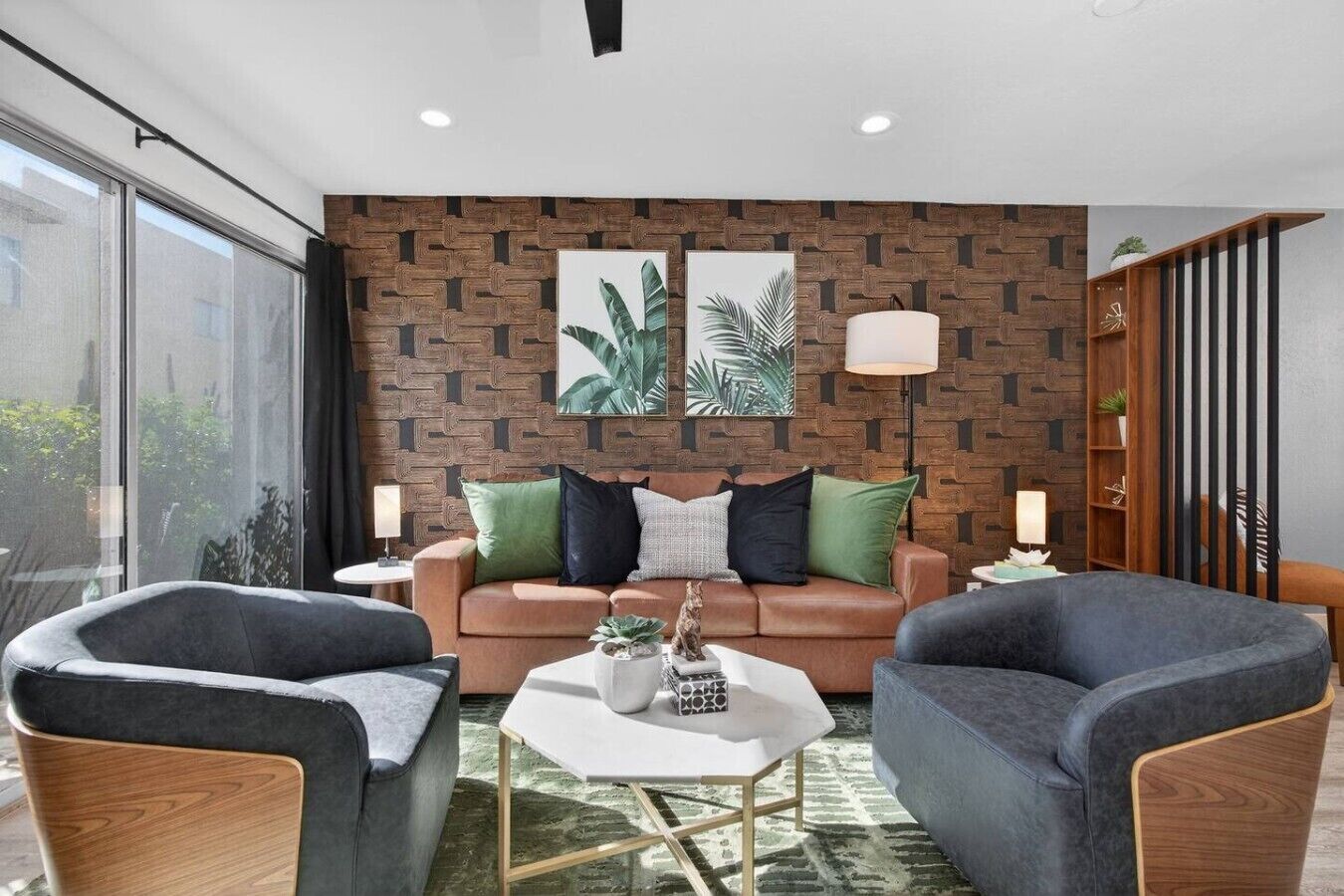 A modern living room with a brown patterned wall, a brown sofa, two armchairs, a coffee table, and two floor lamps.