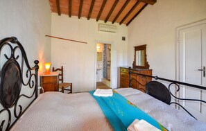 A bedroom with a bed, a dresser, a chair, a lamp, a mirror, and a door. - Beautiful home in Saturnia (Saturnia)