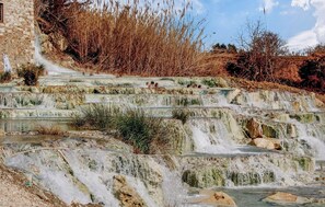 Un escalier en pierre mène à un élément décoratif aquatique, avec un ciel dégagé au-dessus.