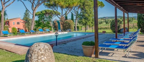 Une piscine avec des chaises longues, une pergola et une structure en pierre.