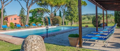 Un espace piscine comprenant des chaises longues, une pergola et une structure en pierre.