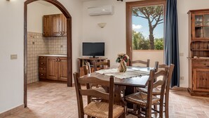 A dining area with a wooden table, chairs, a TV, and a window with a view of trees. - Pet friendly apartment in Roccastrada with WiFi (Roccastrada)