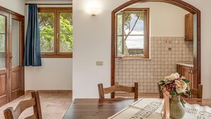 A dining area with a wooden table, chairs, a vase with flowers, and a view through an arched window. - Pet friendly apartment in Roccastrada with WiFi (Roccastrada)