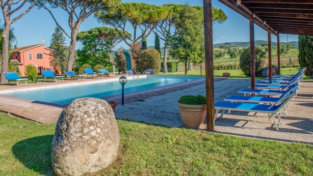 A pool with lounge chairs, a pergola, and a building in the background. - Pet friendly apartment in Roccastrada with WiFi (Roccastrada)