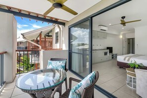 A modern interior with a glass dining table, wicker chairs, a sofa, and a ceiling fan. - Bluewater Hideaway—Lagoon Outlook by Trinity Beach (Trinity Beach)