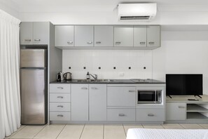 A modern kitchen with a built-in microwave, a coffee maker, and a flat-screen TV. - Bluewater Hideaway—Lagoon Outlook by Trinity Beach (Trinity Beach)