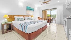 A hotel room with a bed, a desk, a chair, a balcony, and a kitchenette. - Bluewater Hideaway - Lagoon Outlook by Trinity Beach (Trinity Beach)
