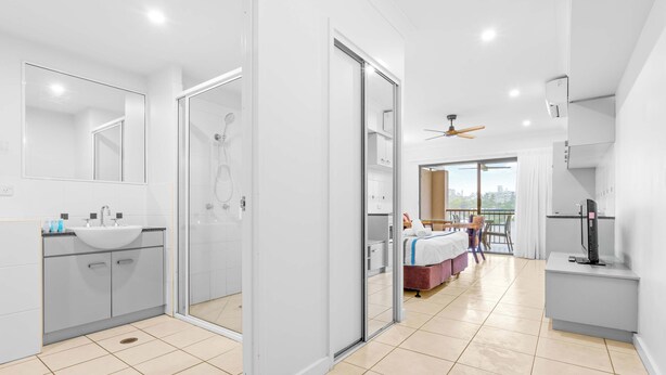 A modern hotel room with a bathroom, a balcony, and a TV. - Bluewater Hideaway - Lagoon Outlook by Trinity Beach (Trinity Beach)
